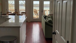 Une cuisine spacieuse dotée d’un grand îlot central, d’un coin repas avec des chaises et d’une vue sur un lac grâce à de grandes fenêtres.