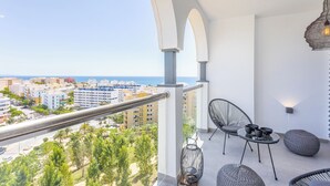 Ein Balkon mit Metallgeländer, Korbstühlen und einem Tisch mit Tassen und Untertassen.