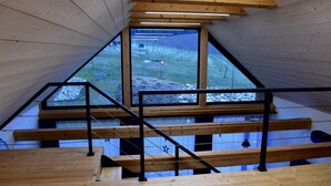 A wooden interior with a sloped ceiling, a large window, and a staircase.