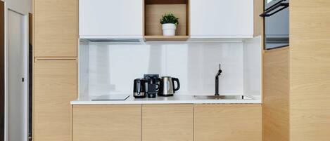 A modern kitchen with wooden cabinets, a white countertop, and a built-in shelf with decorative items.