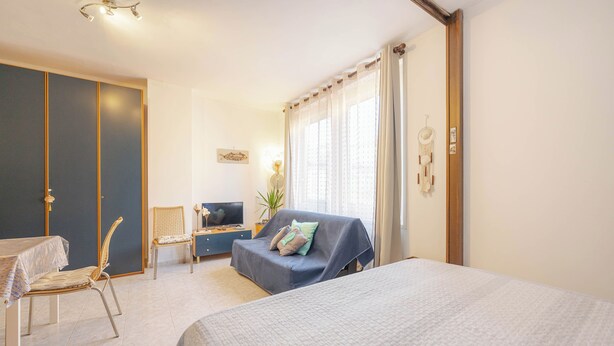 Una habitación de hotel con una cama grande, un escritorio con computadora, una silla, un armario y una ventana con cortinas.