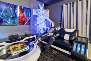 Ein modernes Wohnzimmer mit Wandkunst zum Thema Star Wars, einem weißen Dekobastbaum und einem futuristischen Sessel.