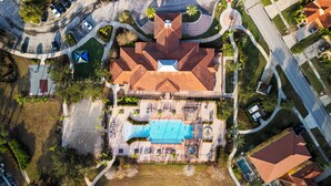 Luchtbeeld van een woonwijk met een zwembad, een tennisbaan en een aangelegde tuin.
