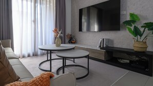 A modern living room with a flat-screen TV mounted on the wall, two round tables, a sofa, and a large window with curtains. - Taipei Main Station Warm & Cozy 2B1b Living, Dining, Kitchen (Taipei City)