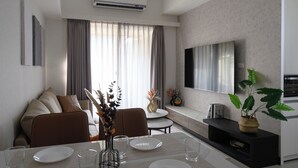 A modern living room with a dining area, a flat-screen TV mounted on the wall, and a large window with curtains. - Taipei Main Station Warm & Cozy 2B1b Living, Dining, Kitchen (Taipei City)