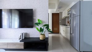 A modern kitchen with a large refrigerator, a flat-screen TV mounted on the wall, and a potted plant on a black console table. - Taipei Main Station Warm & Cozy 2B1b Living, Dining, Kitchen (Taipei City)