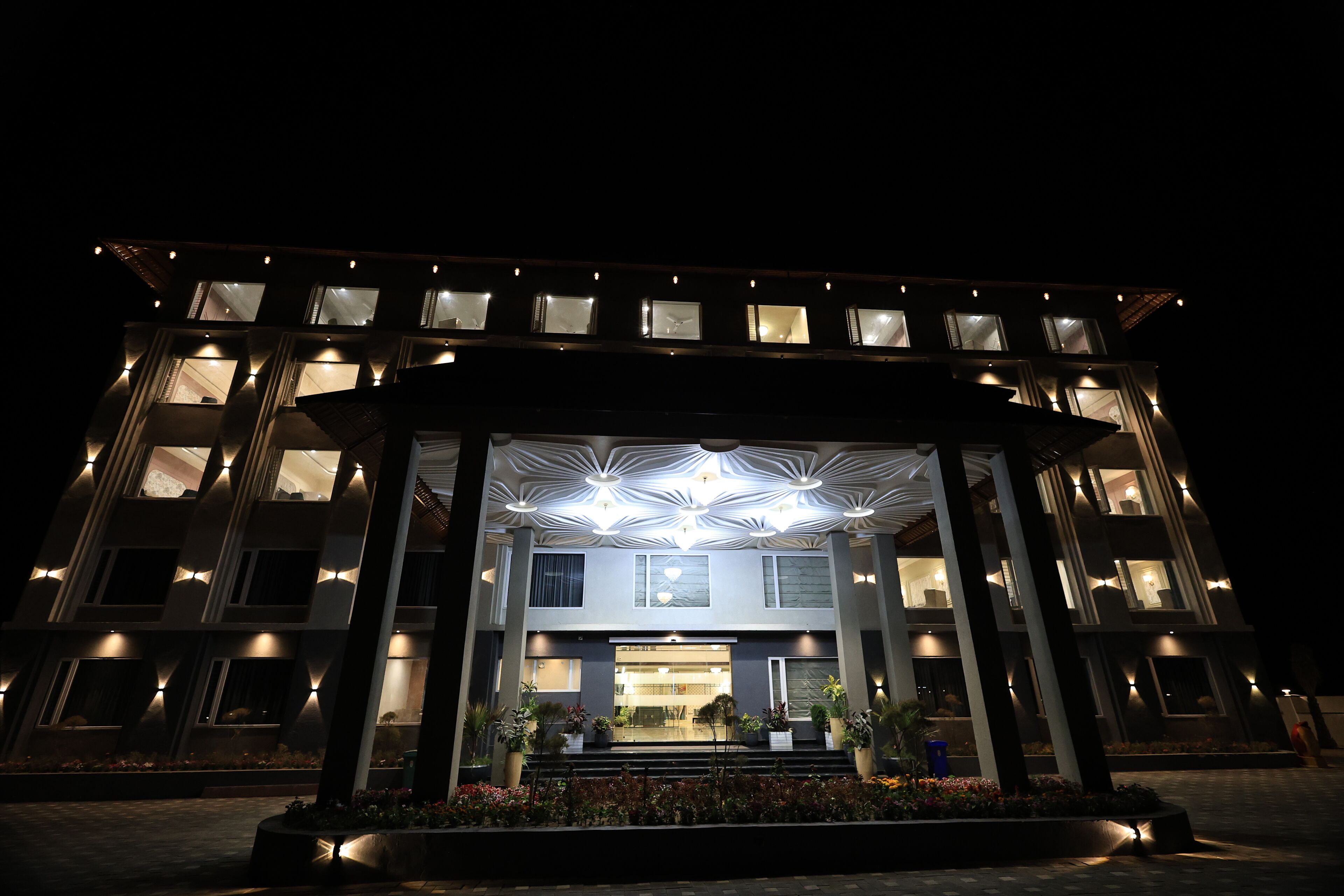 A modern hotel with a symmetrical facade, multiple balconies, and a central entrance with a geometric light fixture.