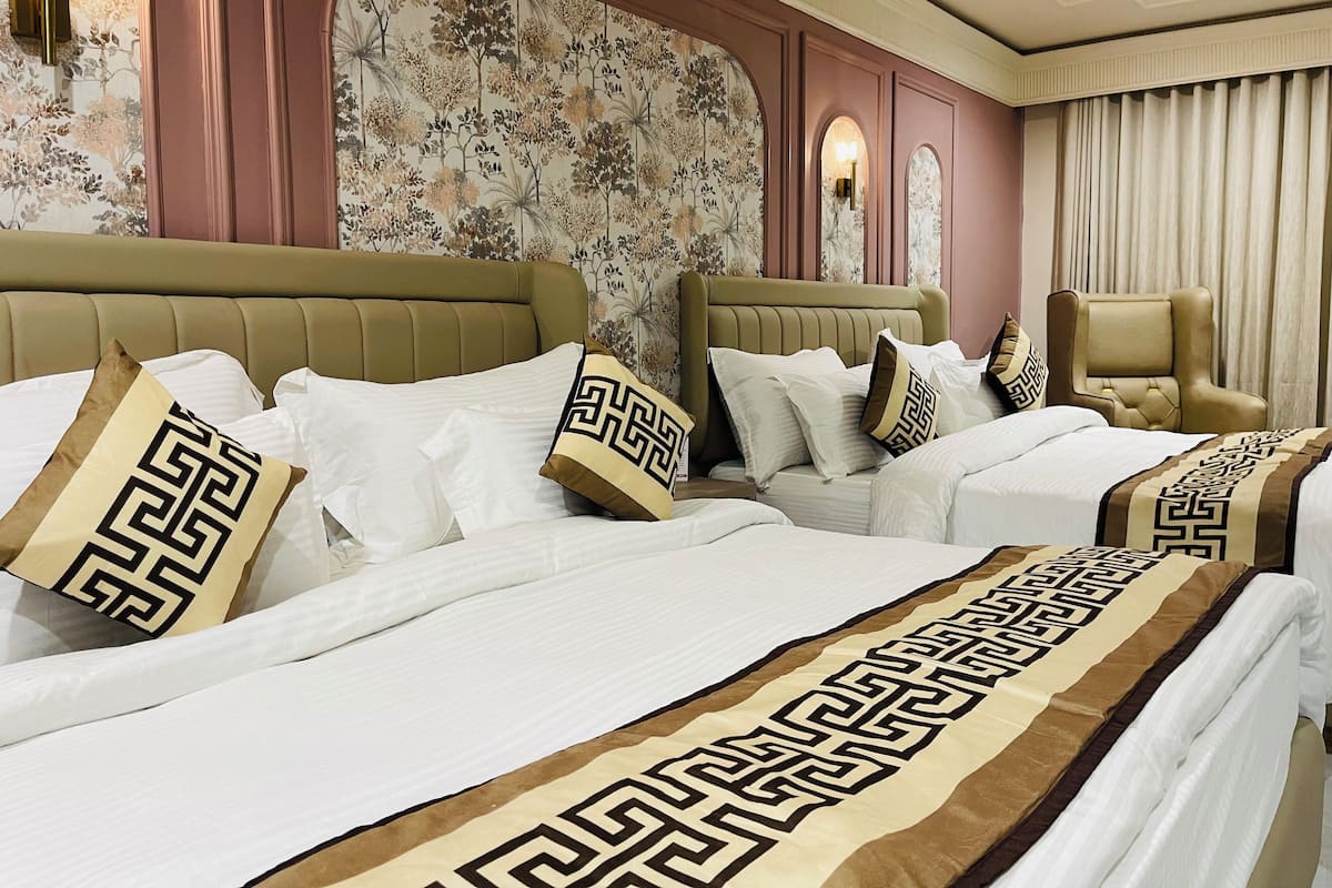 A hotel room with two beds, each with a headboard, and a large window with curtains.