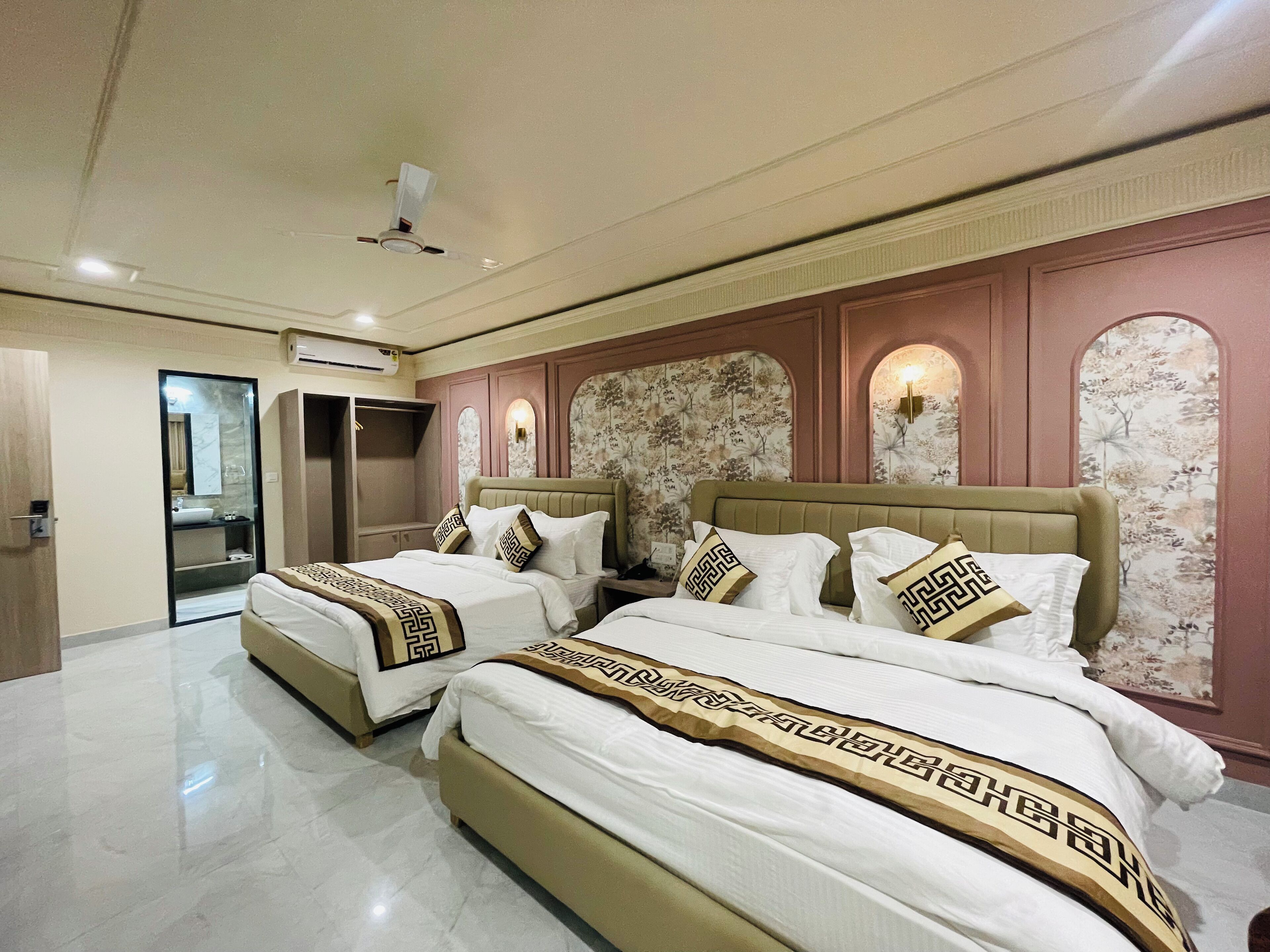 A hotel room with two beds, a wardrobe, a mirror, and a vanity with a sink.