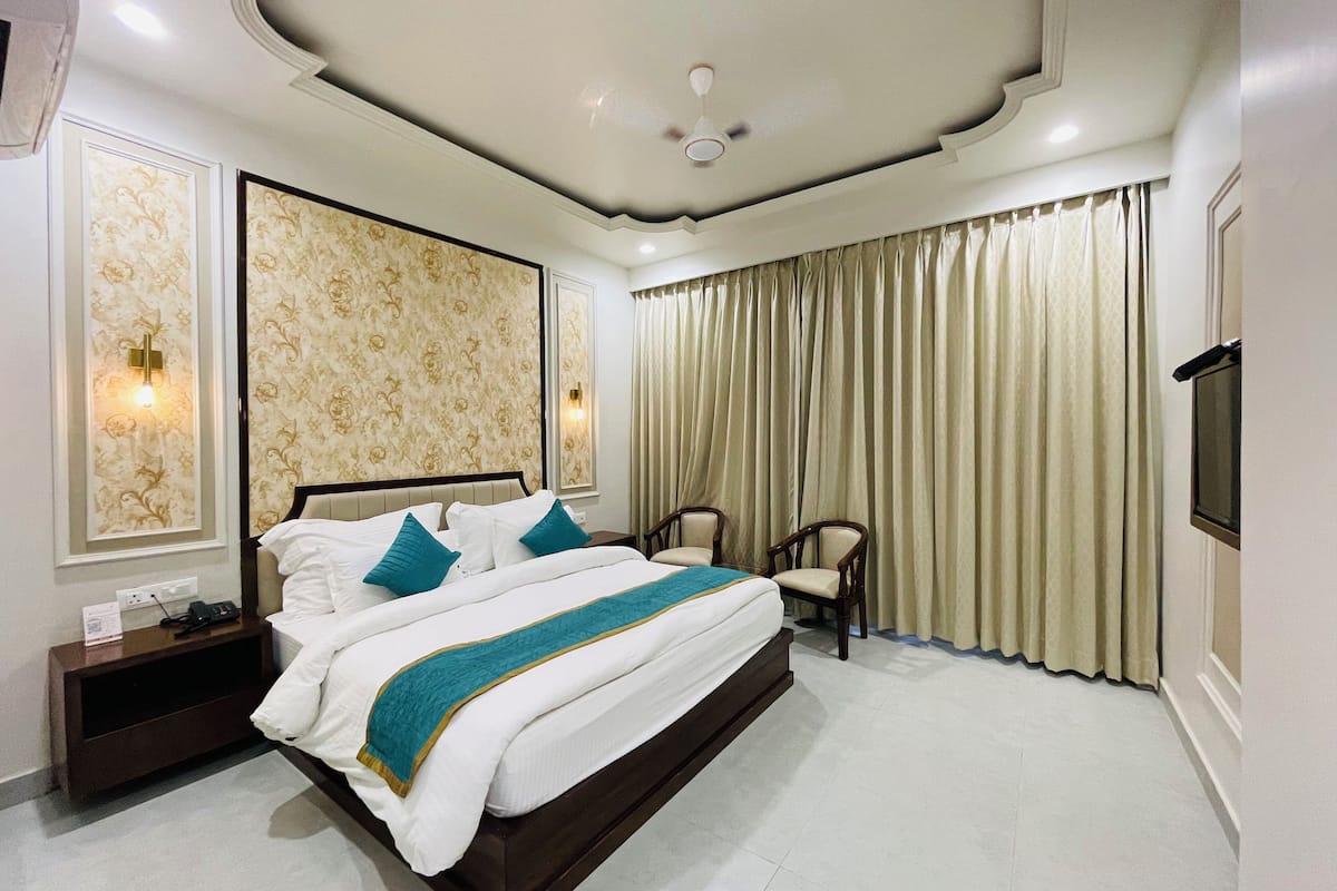 A spacious bedroom with a large bed, two nightstands, a desk, and a chair.