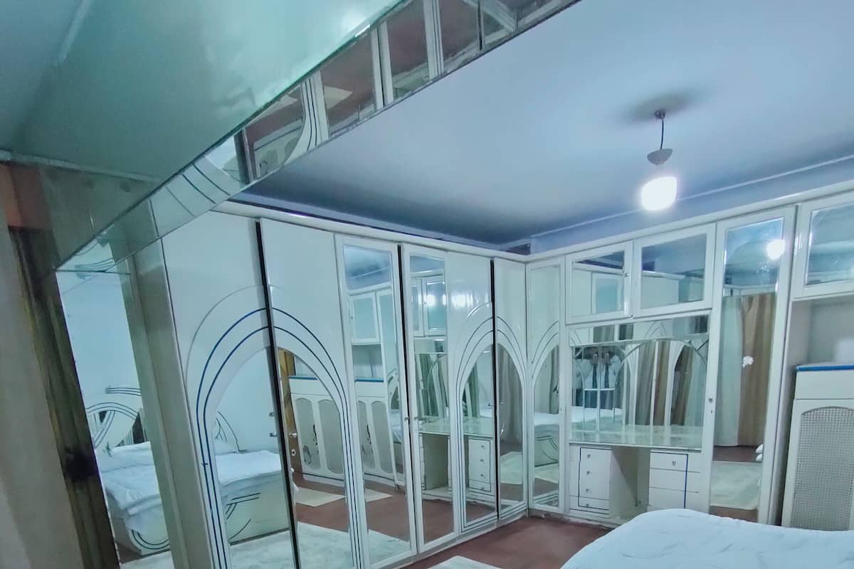 Ein Schlafzimmer mit einem Bett, einem großen Spiegel und einem Kleiderschrank.