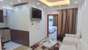A modern hotel room with a sofa, a TV, a small table, and a patterned rug. - HS STIDUS 1 (Giza)