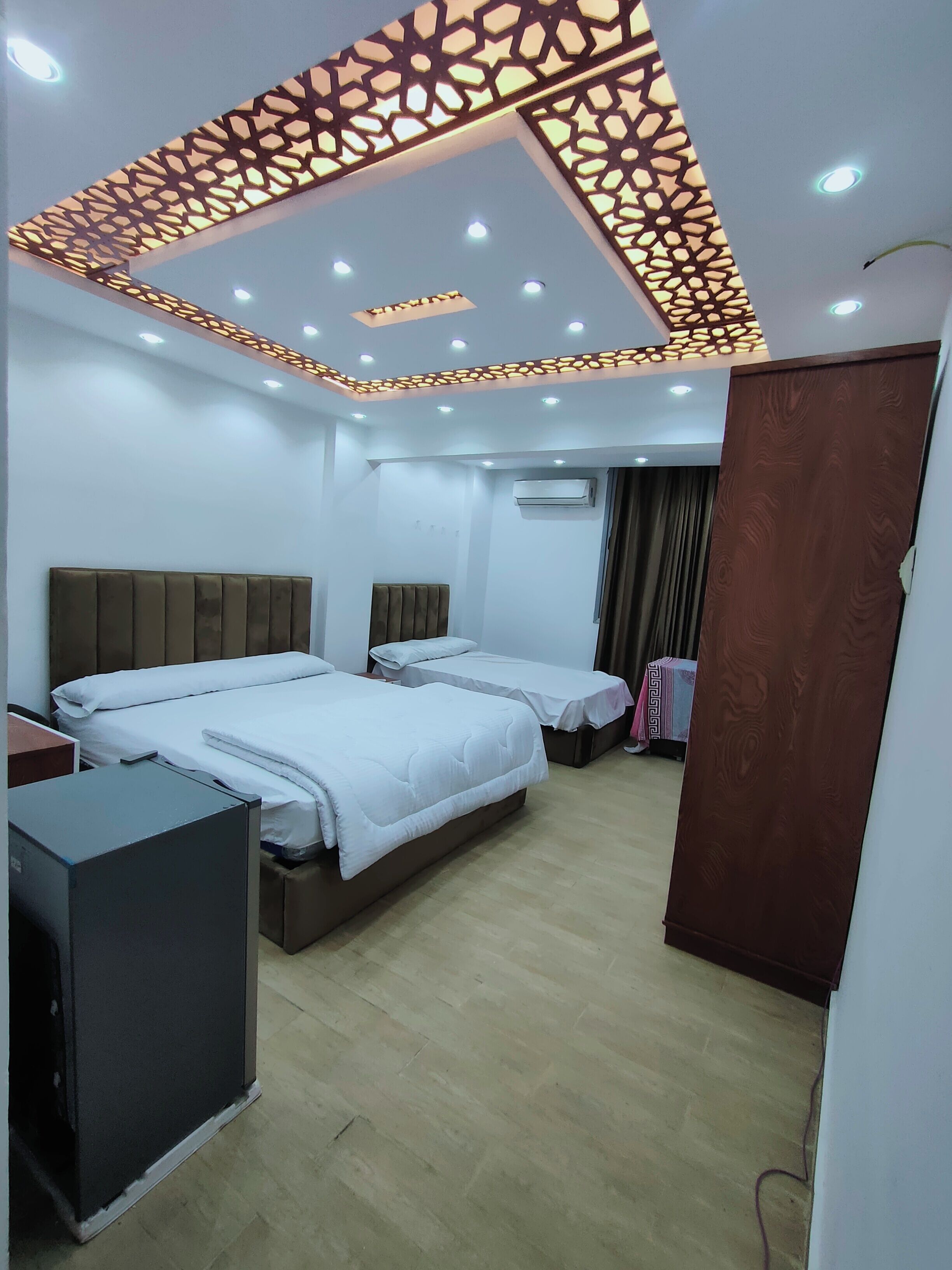 A hotel room with two beds, a desk, and a wardrobe.