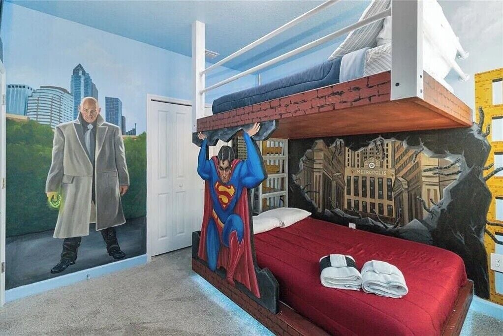 Ein Zimmer mit einer Wandmalerei von Superman und Batman, einem Etagenbett und Blick auf eine Stadtlandschaft.