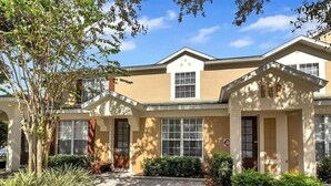 A building with a beige facade, multiple windows, and a central entrance. - Minutes to Disney, Free Water Park & Private Pool 3-bedroom townhome (Kissimmee)