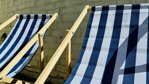 Two striped beach chairs with wooden frames and fabric seats, positioned against a brick wall. - Magenta Melodies, 5 bedroom house with 2 free parking spaces  (Blackpool)