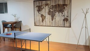 A ping pong table in a room with a wooden floor, a world map mural, and a tripod stand. - 9 minutes from the airport cozy basement (Calgary)