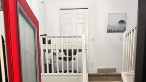 A staircase leading to a loft bedroom with a red door and a small window. - 9 minutes from the airport cozy basement (Calgary)