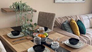 A dining table set with black bowls, plates, and cutlery, surrounded by chairs and a potted plant. - Rosa Amarilla Apartment (Puerto Rico)