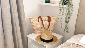 A neatly arranged bedroom with a bed, a nightstand, a hanging plant, and a woven basket with a hat on it. - Rosa Amarilla Apartment (Puerto Rico)
