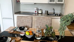 A modern kitchen with white cabinets, a sink, and a countertop. There is a dining table set with plates, bowls, and a pitcher of water. - Rosa Amarilla Apartment (Puerto Rico)
