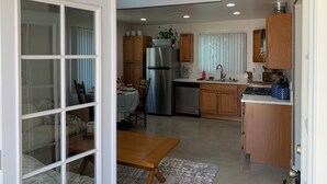 Una cocina moderna con armarios de madera, un refrigerador de acero inoxidable y un comedor con una mesa y sillas.