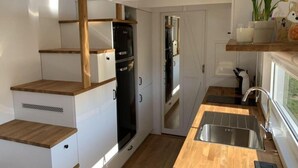 Eine kleine Küche mit weißen Schränken, einem schwarzen Kühlschrank und einer Holz Arbeitsplatte.
