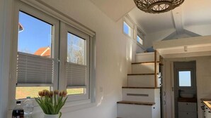 Eine moderne Küche mit weißem Arbeitsplatz, einem eingebauten Herd und einem Fenster mit Jalousien.