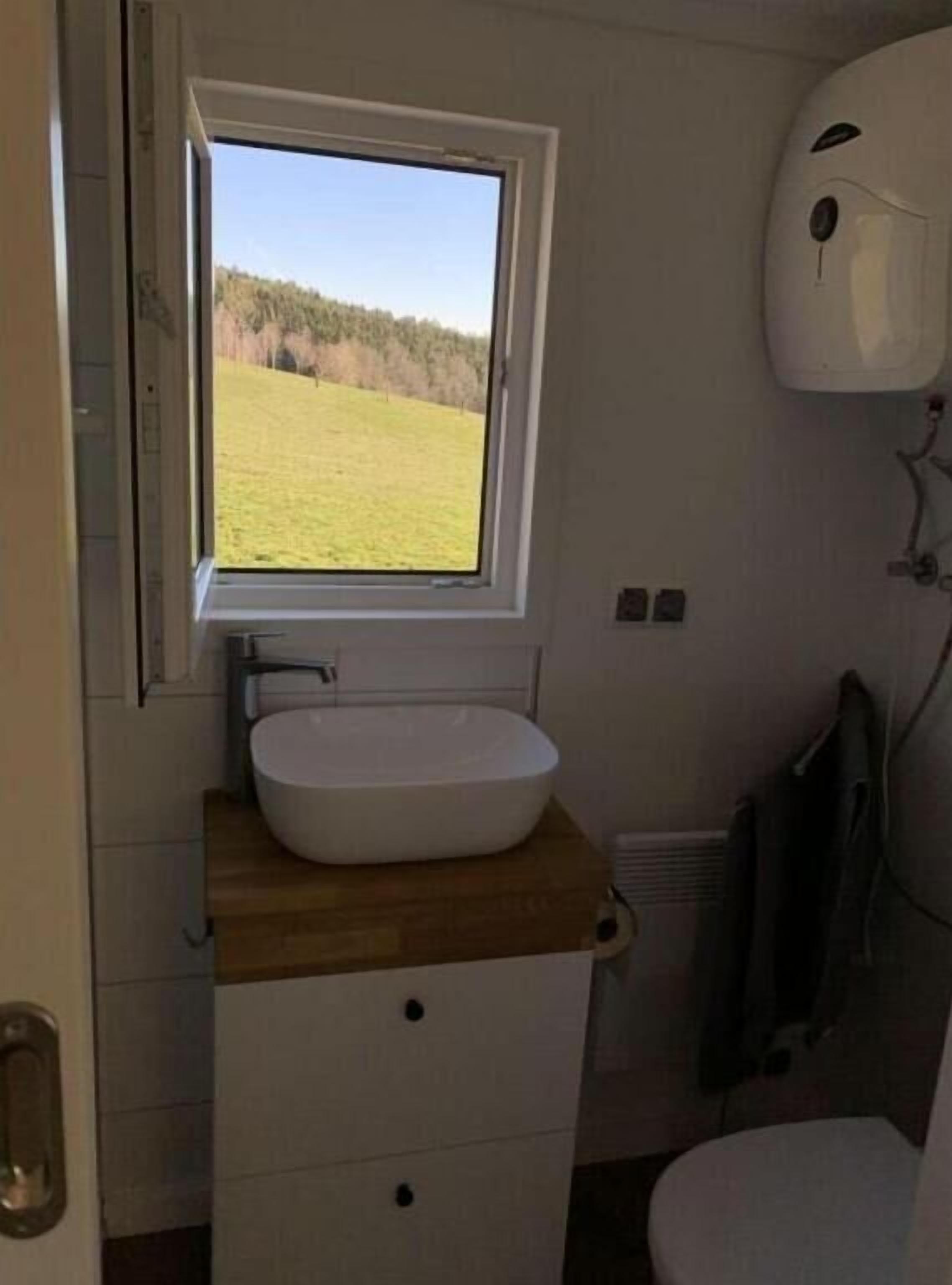 Een badkamer met een raam, een wastafel en een toilet.