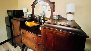A wooden dresser with a mirror, a small TV, and decorative items.