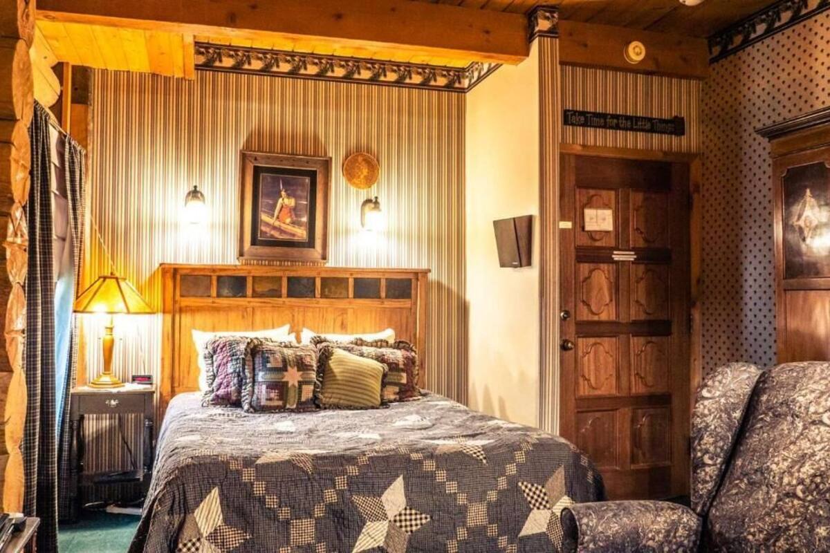 Una habitació acollidora amb un llit, una làmpada, un quadre amb marc i una porta de fusta.