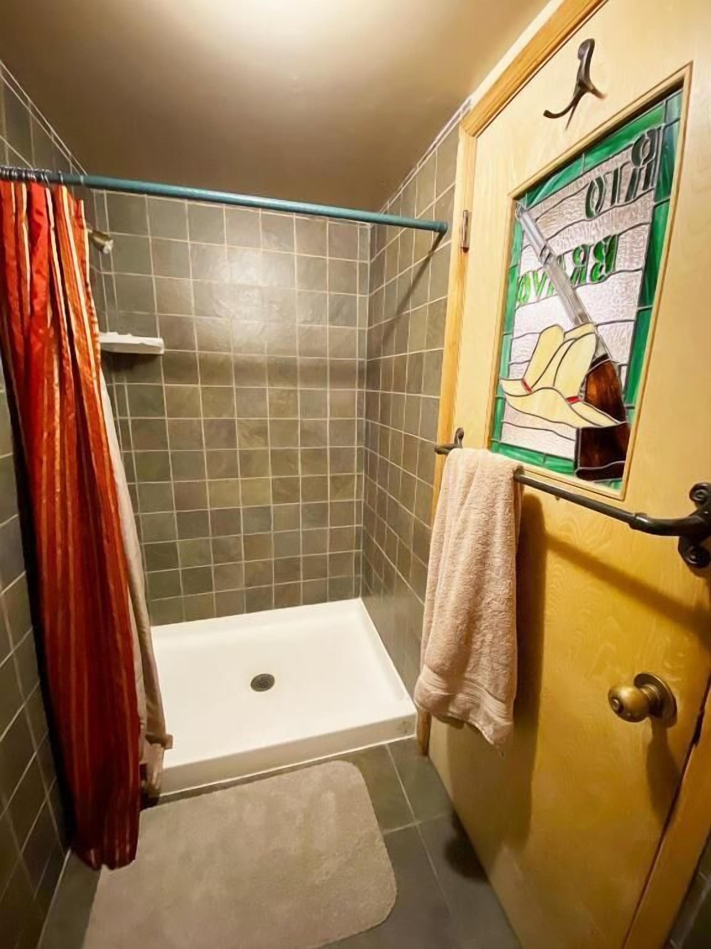 A shower with a glass door, a towel hanging on the door, and a shower curtain.