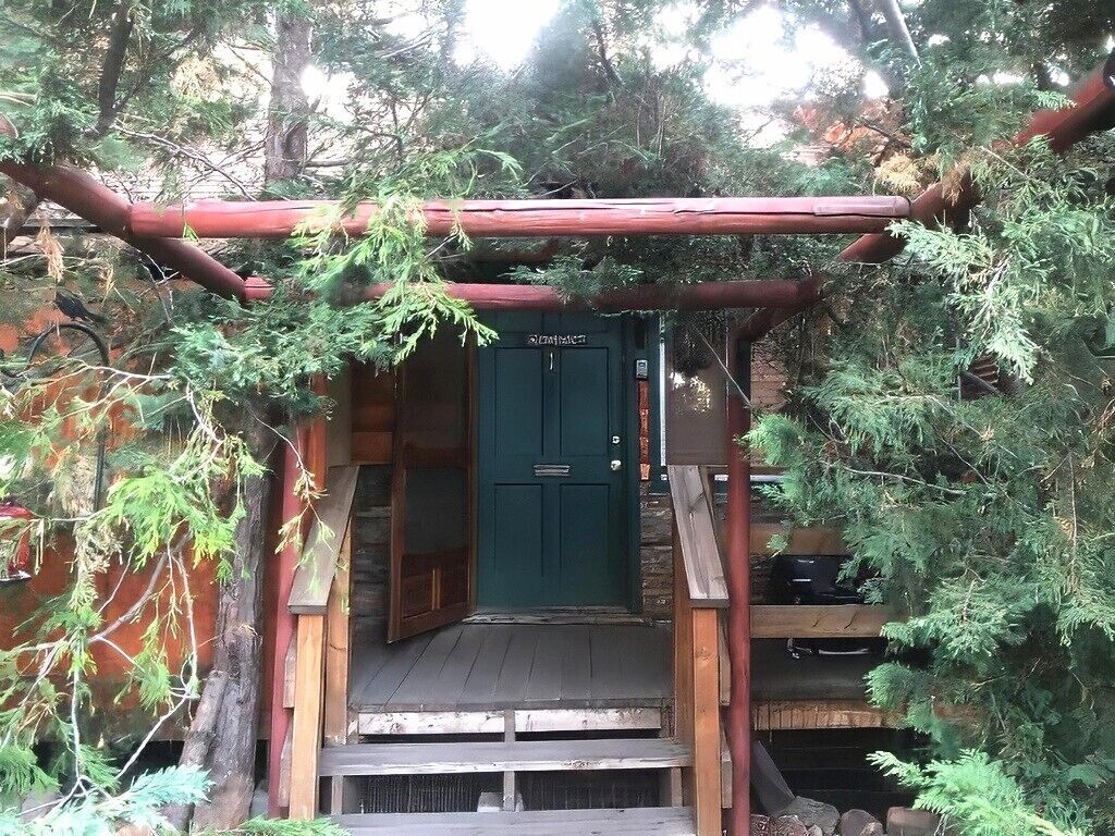 A wooden staircase leading to a green door with a sign above it.