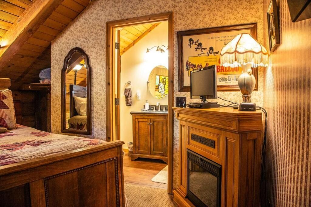 A cozy room with a wooden ceiling, a fireplace, a television, and a mirror.