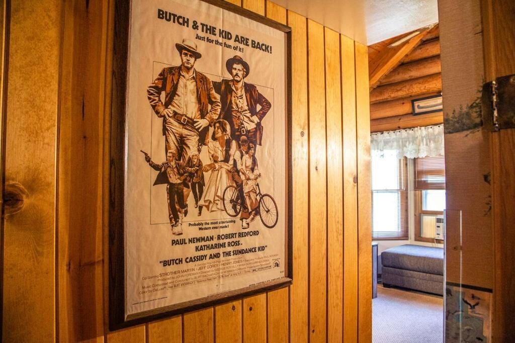 En plakat af 'Butch Cassidy and the Sundance Kid' i et træpaneleret rum med seng og vindue.
