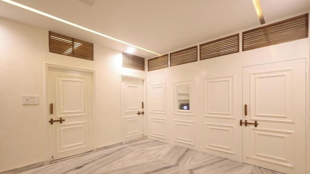 Un pasillo con puertas blancas, listones de madera en el techo y un suelo con diseño.