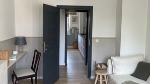 Un salon moderne avec un canapé, un fauteuil, une lampe et un tapis à carreaux.