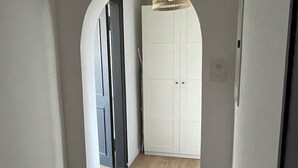 Un couloir avec un plancher en bois, des murs blancs et une porte blanche au fond.