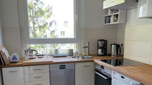 Une cuisine moderne dotée de plans de travail en bois, d’un lave-vaisselle, d’une machine à laver et d’une fenêtre laissant entrer la lumière naturelle.