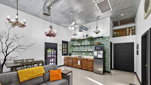 Un interior moderno con un sofá gris, una mesa de comedor de madera y una cocina con salpicadero de estilo estampado en verde.