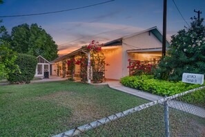 A residential property with a well-maintained lawn, a gated entrance, and a house number sign.