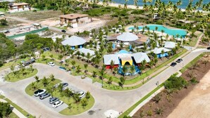 Ein Luftbild eines Resorts mit Schwimmbad, mehreren Gebäuden und einem Strand.