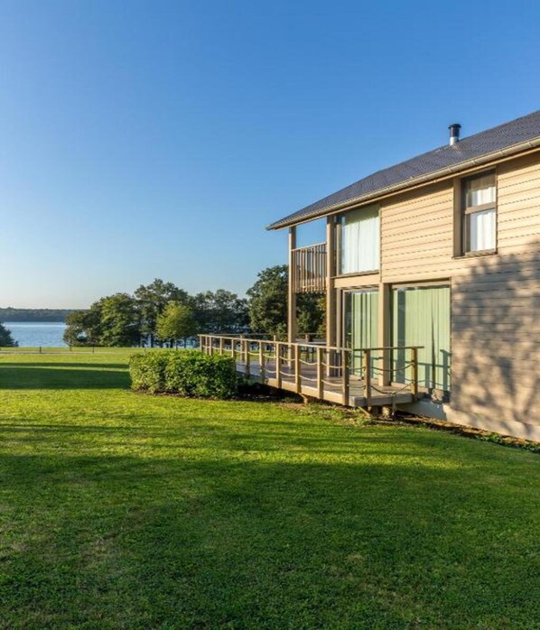 A two-story house with a balcony, a lawn, and a view of a lake. - Spacious Villa Near Castle (Froidchapelle)