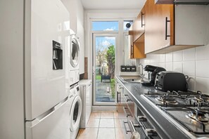 A compact kitchen with a built-in washer, a gas stove, and a view through the door to the outside.