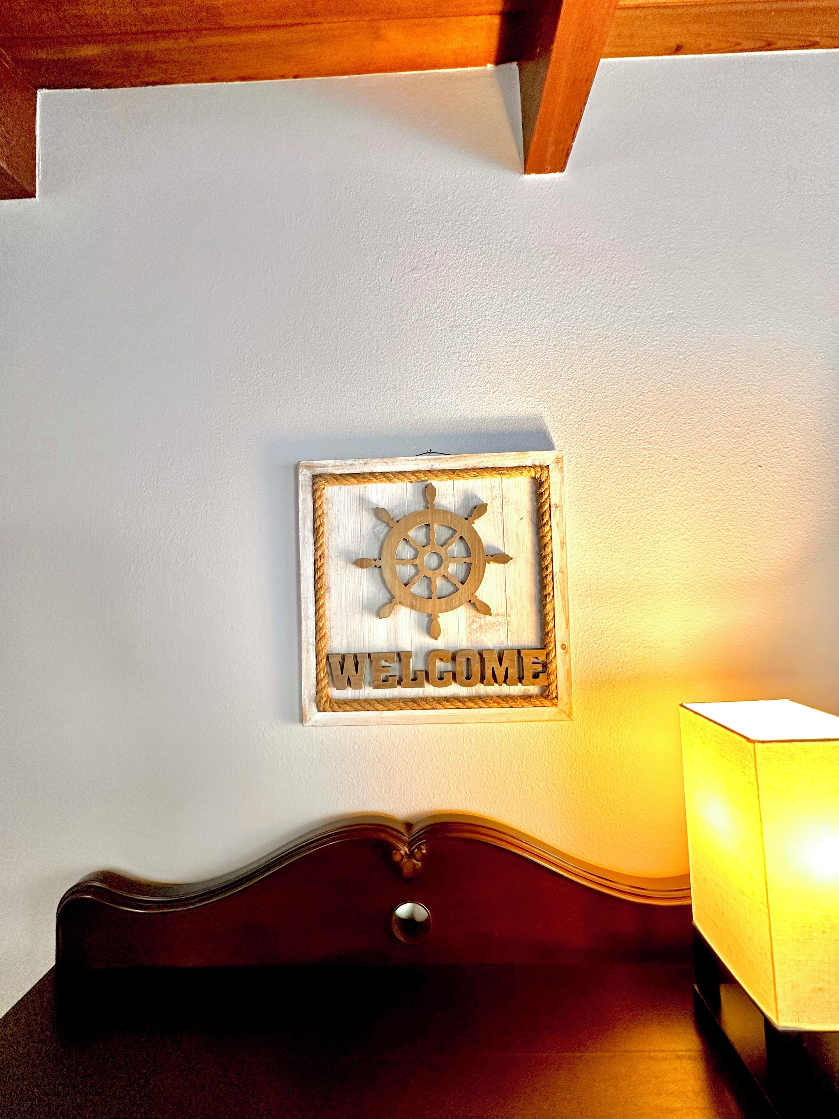 A welcome sign with a ship's wheel design and the word "WELCOME" on a wall.