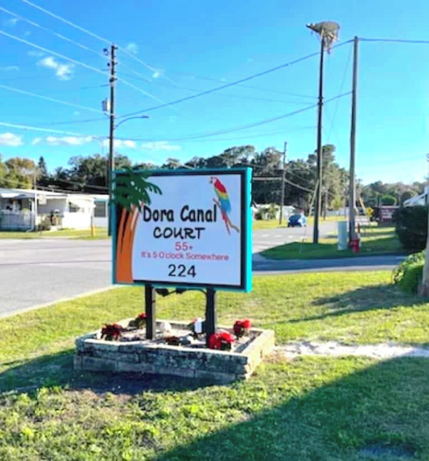 A sign for Dora Canal Court, number 224, with a palm tree and parrot illustration.