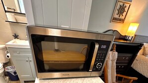A kitchen with a built-in microwave, a drawer unit, and a wooden chair. - Cottage 34: Coconut Cottage - Waterfront Lodging in Downtown Tavares, FL (Tavares)