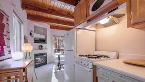 Une cuisine avec des poutres en bois, une cuisinière à gaz, un four encastré et un réfrigérateur.