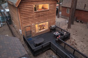 Eine Holzhütte mit einer Terrasse, einer Feuerstelle und einer überdachten Sitzgruppe im Freien.