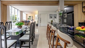 A modern kitchen with a central island, black appliances, and a dining area with a glass table and chairs.